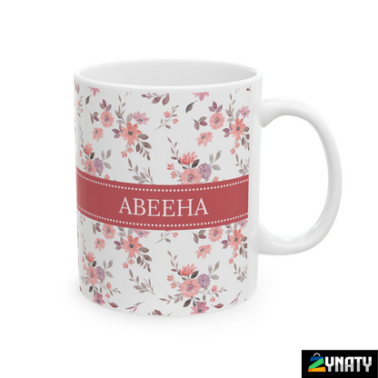 A white ceramic mug with floral patterns and a personalized name 'ABEEHA' printed on both sides.