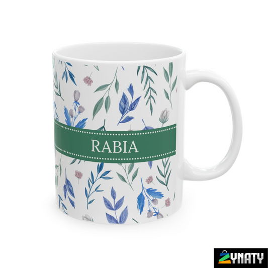 A white ceramic mug with a green handle, featuring a floral pattern and the name 'RABIA' printed in green on both sides.